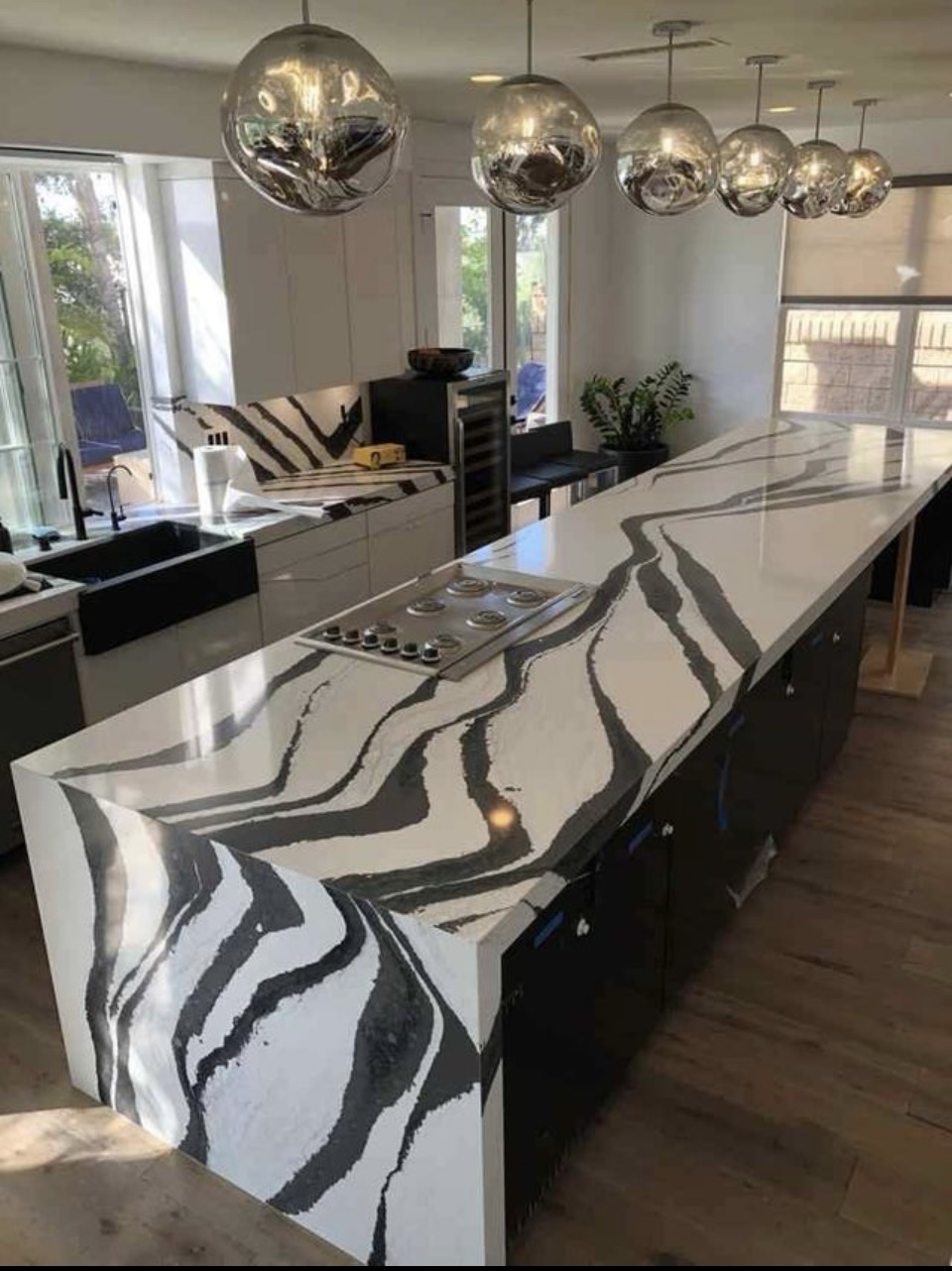 Kitchen remodel with black and white marble waterfall island and glass globe pendants