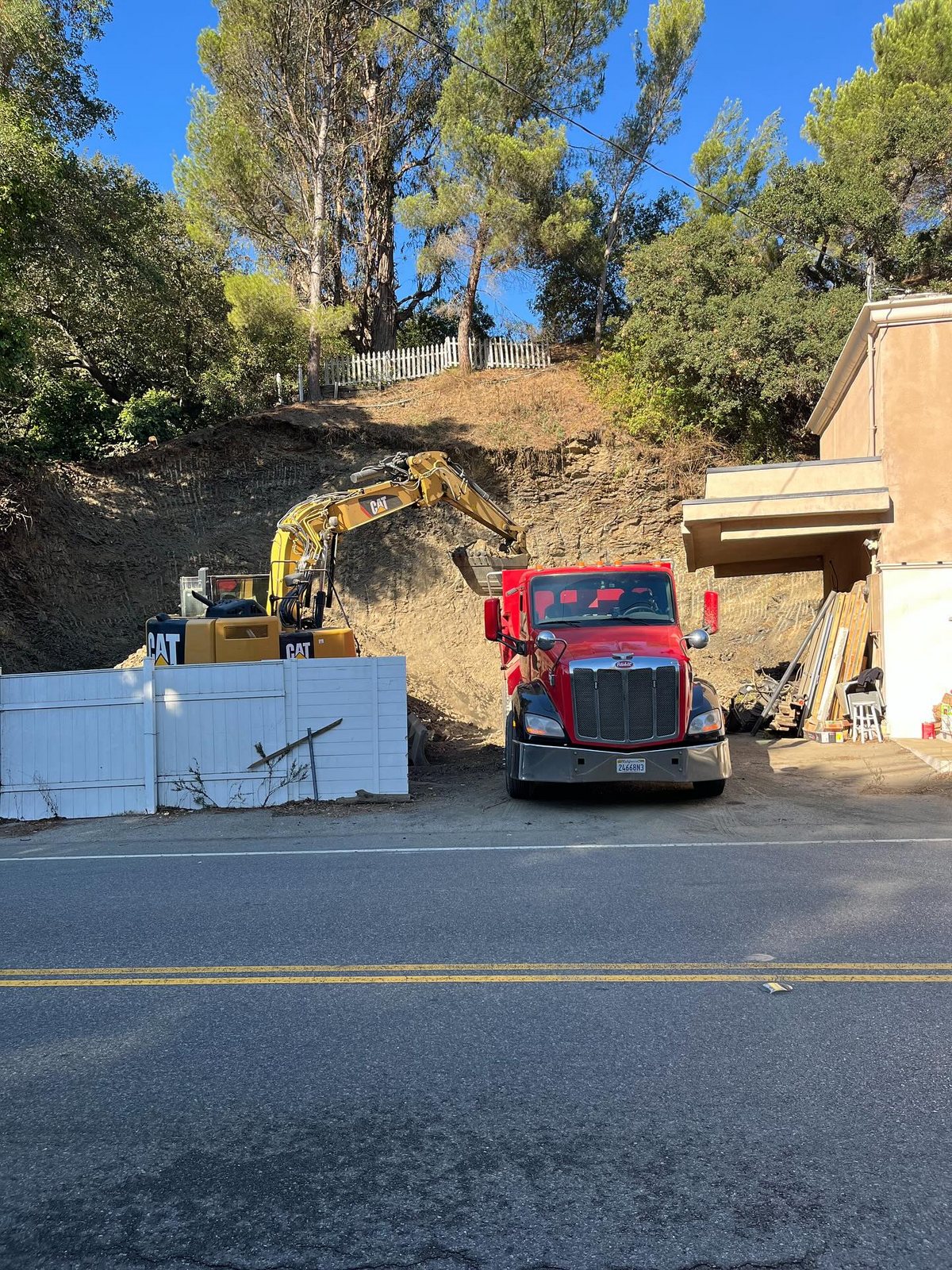 Excavator and dump truck working on a Los Angeles hillside construction site